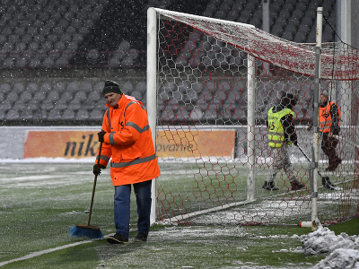 Pracovníci odhŕňajú sneh z hracej plochy po tom, čo hlavný rozhodca v 20. minúte prerušil zápas pre nespôsobilý terén