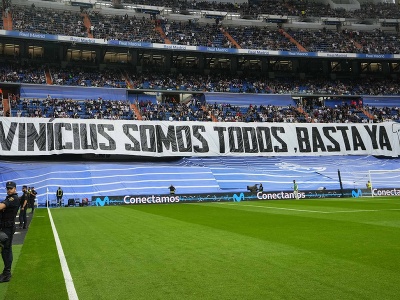 Fanúšikovia stoja pred transparentom, ktorým podporujú brazílskeho  futbalistu Viniciusa Juniora z Realu Madrid 