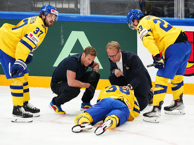 Otrasený švédsky hokejista Rasmus Sandin leží na ľade po súboji s Američanom Michaelom Eyssimontom