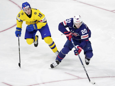 Americký hokejista Lane Hutson (vpravo) a hráč Švédska Isak Rosén bojujú o puk