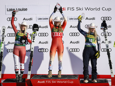 Švajčiarka Corinne Suterová oslavuje na pódiu víťazstvo v úvodnom super-G v Lake Louise, vľavo druhá Rakúšanka Cornelia Hütterová, vpravo tretia Nórka Ragnhild Mowinckelová.
