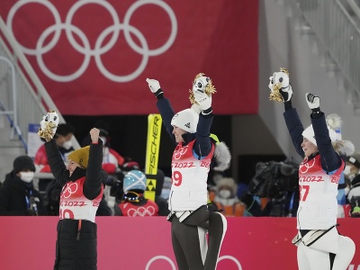 Na snímke uprostred slovinská skokanka na lyžiach Urša Bogatajová oslavuje zisk zlatej medaily v súťaži žien na strednom mostíku na zimných olympijských hrách ZOH 2022 