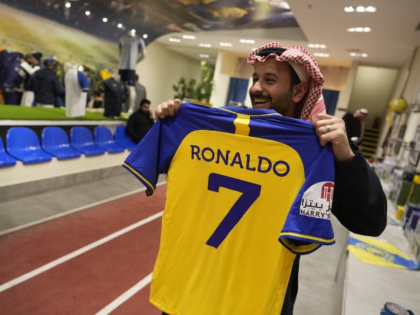 Muž drží futbalový dres Cristiana Ronalda v obchode futbalového klubu Al-Nassr FC v saudskoarabskom Rijáde