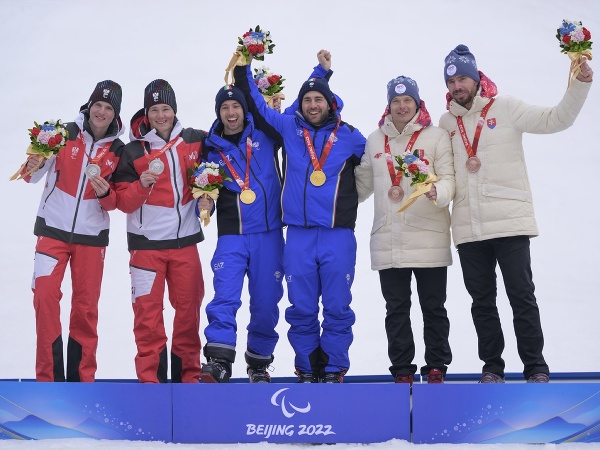  Slovenský reprezentant v paraalpskom lyžovaní Miroslav Haraus (druhý sprava) a navádzač Maroš Hudík (vpravo) pózujú s bronzovými medailami, ktoré získali v slalome zrakovo znevýhodnených na zimných paralympijských hrách v Pekingu