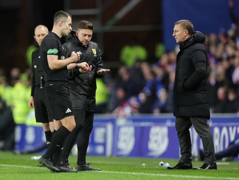 Rozhodca Don Robertson a tréner Celticu Brendan Rodgers počas zápasu proti Rangers riešia hodenú mincu do tváre Arneho Engelsa