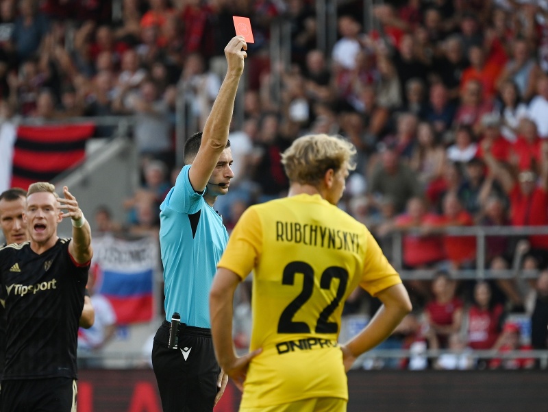 Na snímke uprostred albánsky hlavný rozhodca Juxhin Xhaja udeľuje červenú kartu, vpravo jej adresát a hráč Dnipra Eduard Sarapij v piatej minúte v prvom zápase play off Európskej konferenčnej ligy