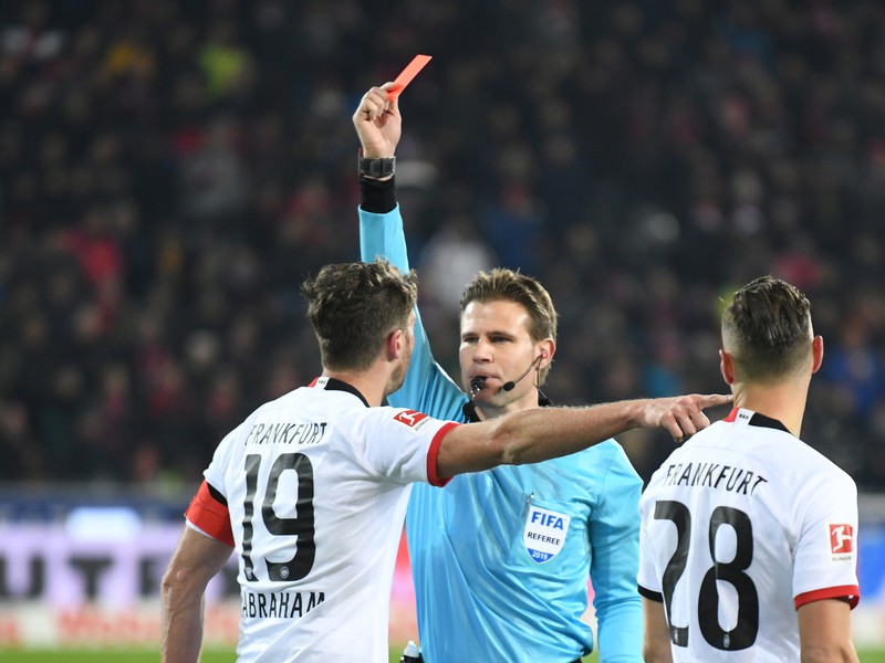 Hlavný rozhodca Felix Brych ukazuje červenú kartu kapitánovi Eintrachtu Frankfurt Davidovi Abrahamovi za vrazenie do trénera Freiburgu Christiana Streicha