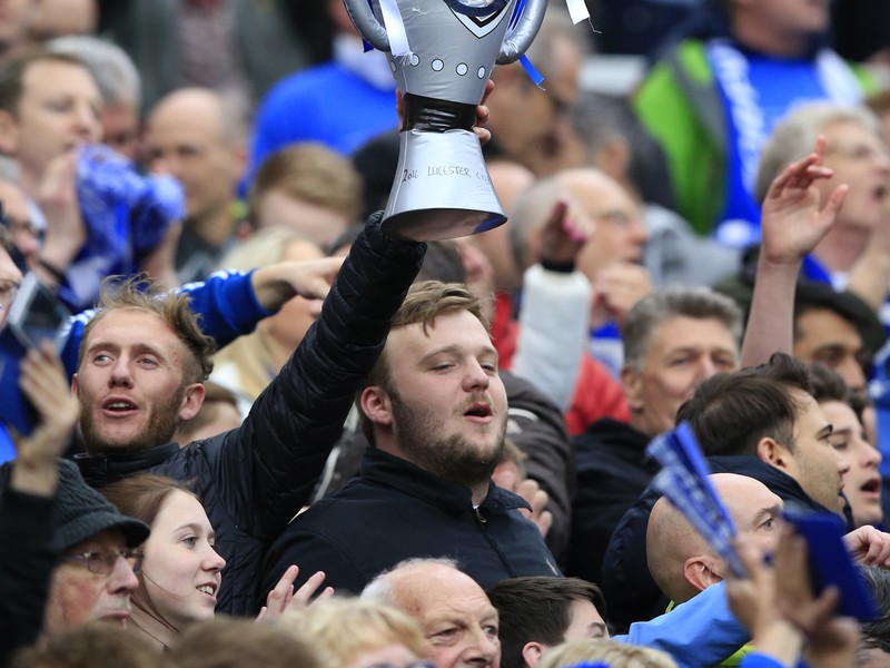 Fanúšikovia v hľadisku s imitáciou trofeje Premier League
