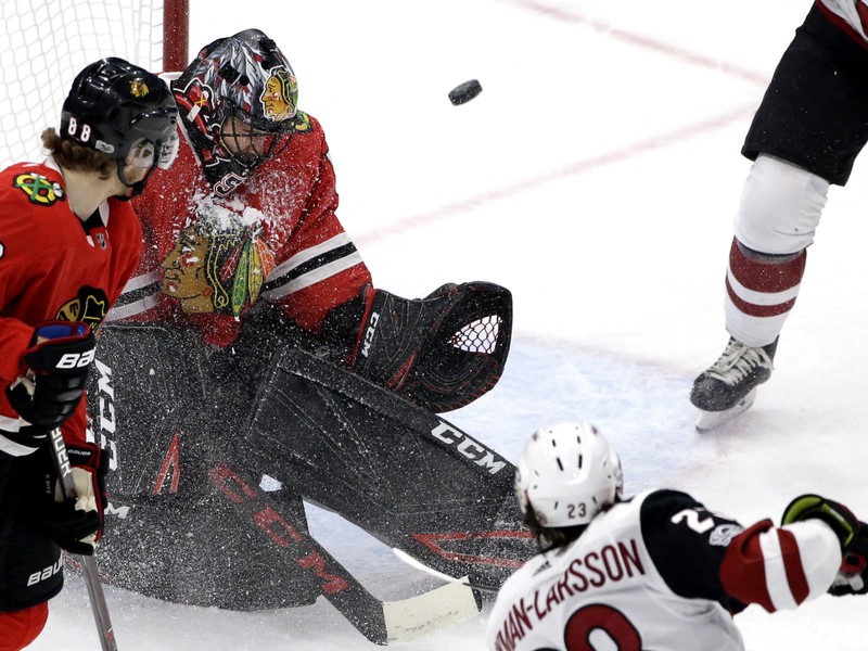 Brankár Chicaga Corey Crawford likdivduje strelu hráčov Arizony.