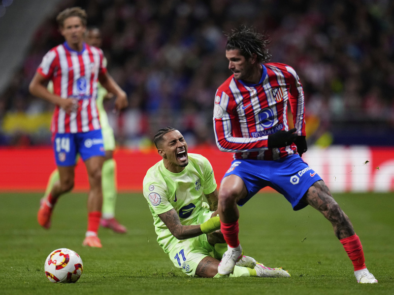 Hráč Barcelony Raphinha (vľavo dole) padá v súboji s Rodrigom De Paulom z Atlética Madrid