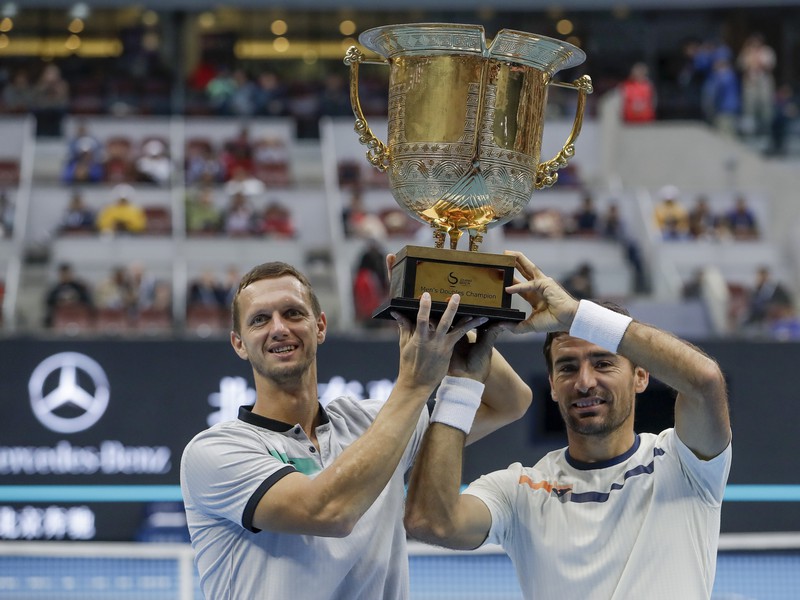 Slovensko-chorvátsky deblový pár Filip Polášek (vľavo) a Ivan Dodig pózujú s trofejou po zisku titulu