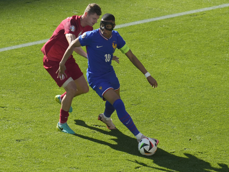 Francúz Kylian Mbappe (vpravo) s maskou na tvári a hráč Poľska Pawel Dawidowicz bojujú o loptu
