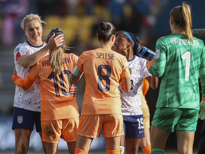 Americké futbalistky (biele dresy) a Holanďanky (oranžové dresy) si podávajú ruky po zápase základnej E-skupiny