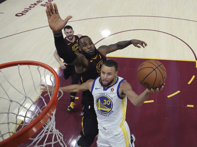 Hráč Goldenu State Warriors Stephen Curry (vpravo) strieľa na kôš cez LeBrona Jamesa z Clevelandu Cavaliers