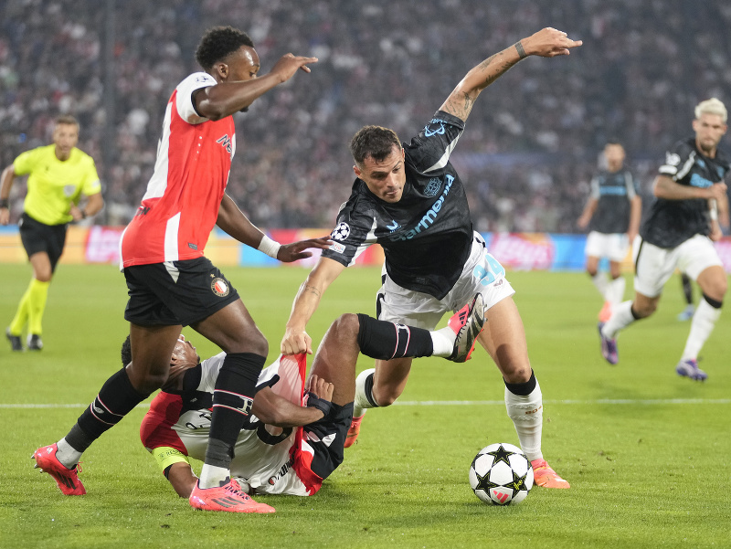 Hráč Feyenoordu Rotterdam Quinten Timber (dole), Antoni Milambo (vľavo) a hráč Leverkusenu Granit Xhaka v súboji o loptu