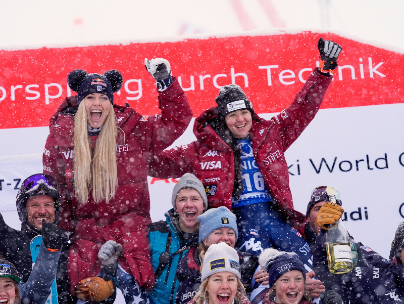 Lindsey Vonnová (hore vľavo) a jej krajanka Jacqueline Wilesová (hore vpravo), ktorá skončila na treťom mieste, sa tešia s členmi svojho tímu po zjazde Svetového pohára alpských lyžiarok