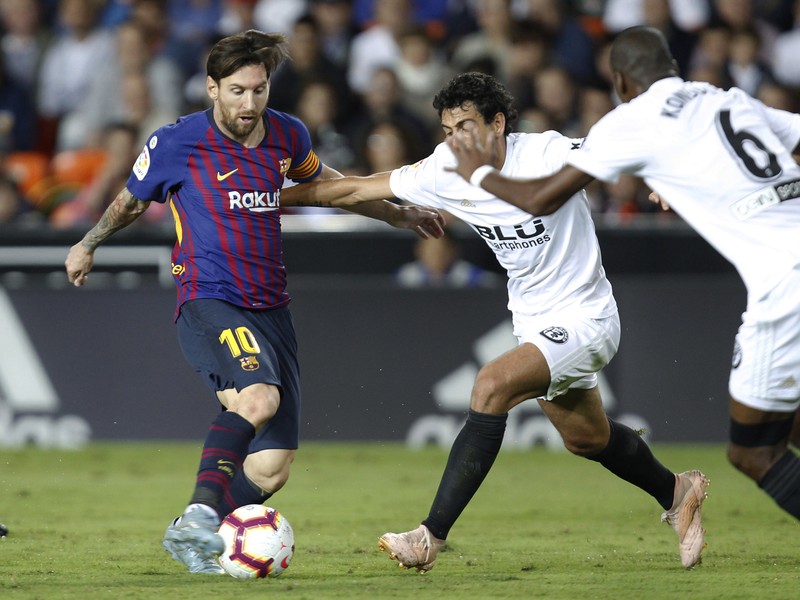 Lionel Messi a Daniel Parejo v súboji o loptu