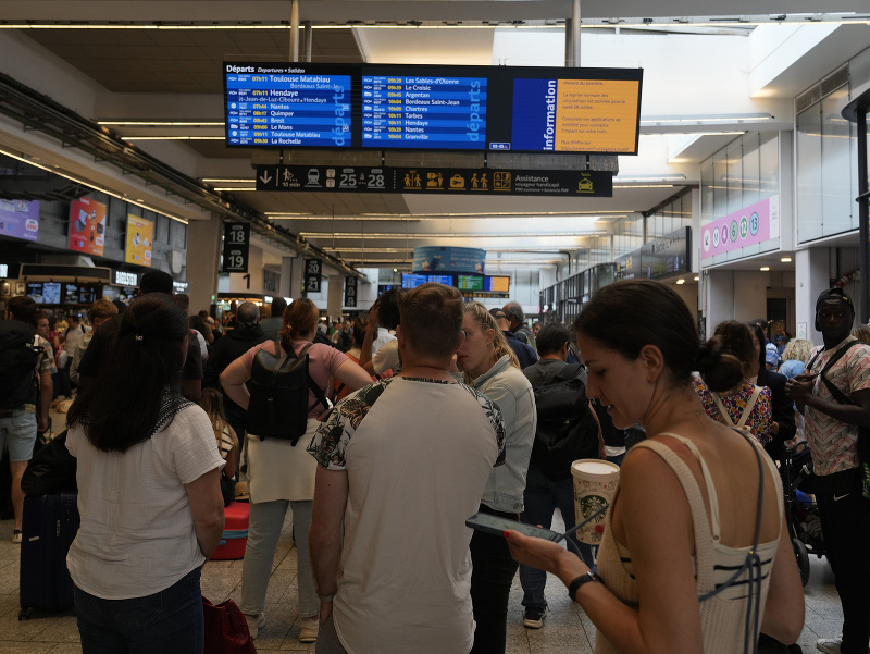 Cestujúci si prezerajú odchody a príchody vlakov na informačnej tabuli železničnej stanice v Paríži