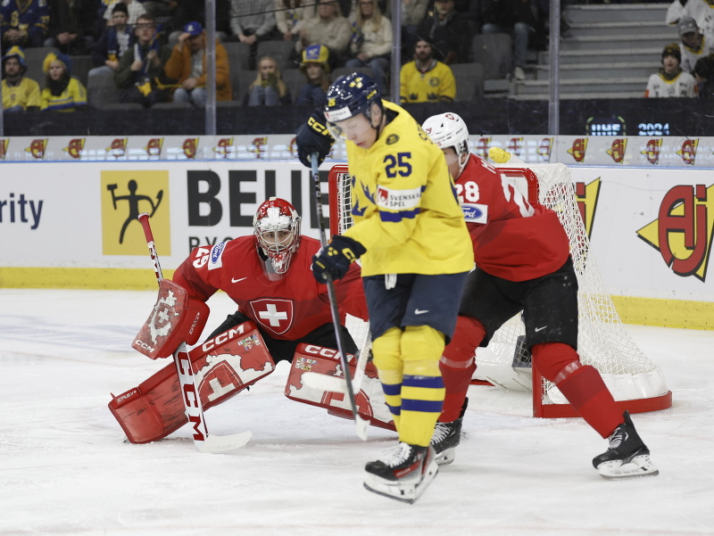 Švédsky hokejista Otto Stenberg (uprostred) prekonáva švajčiarskeho brankára Alessia Beglieriho