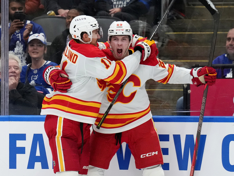 Samuel Honzek sa teší zo svojho prvého gólu v NHL, spolu s ním kapitán Calgary Mikael Backlund