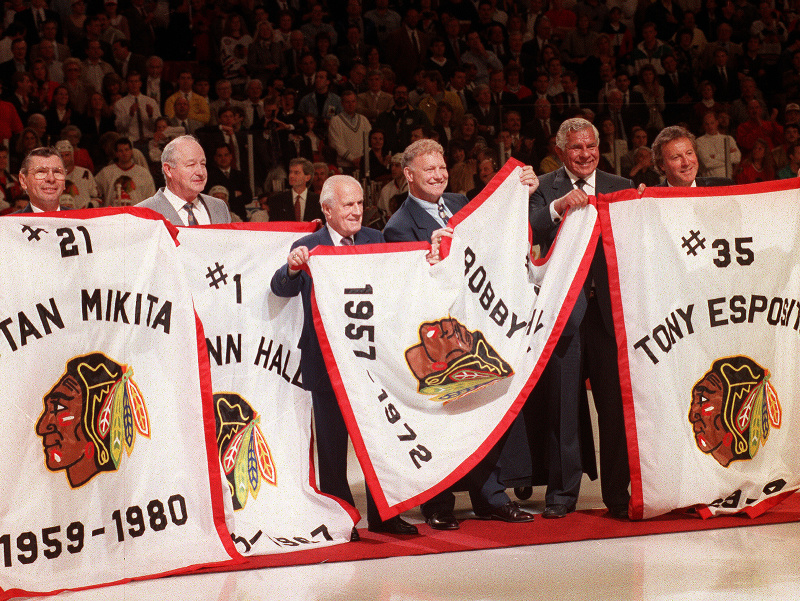 Na archívnej snímke z 14. apríla 1994 Glenn Hall (druhý vľavo) stojí s bývalými hráčmi Chicaga Blackhawks Stanom Mikitom,  bývalým generálnym manažérom Tommym Ivanom, Bobbym Hullom, Billom Wirtzom a Tonym Espositom počas slávnostného ceremoniálu pred zápa
