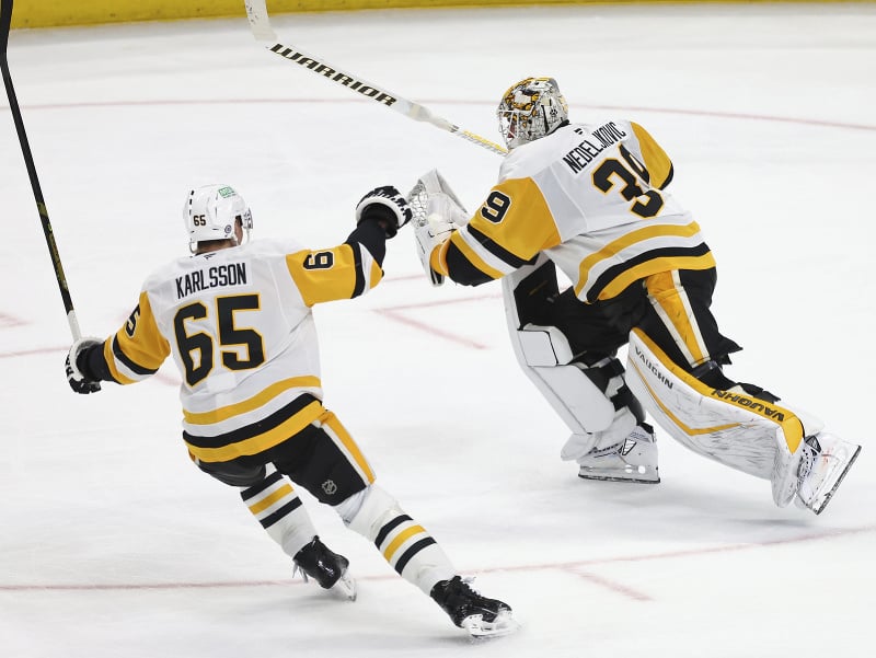 Brankár Pittsburghu Alex Nedeljkovic sa teši po tom, čo vsietil gól cez celé ihrisko, vedľa neho Erik Karlsson