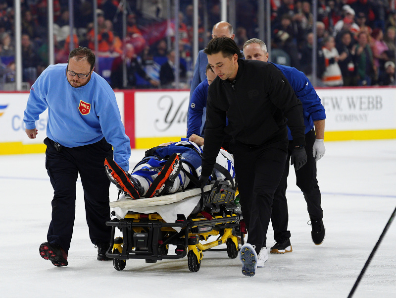 Obrancu Chrisa Taneva z Toronta Maple Leafs odvážajú z ľadu na nosidlách po zrážke s Matvejom Mičkovom z Philadelphie