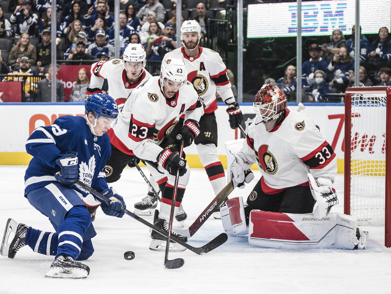 Brankár Cam Talbot sa snaží čeliť Pontusovi Holmbergovi z tímu Toronto Maple Leafs 