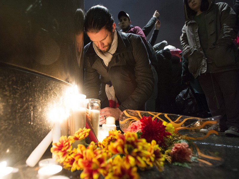 Ľudia zapaľujú sviečky na pamiatku obetí teroristického útoku v Paríži