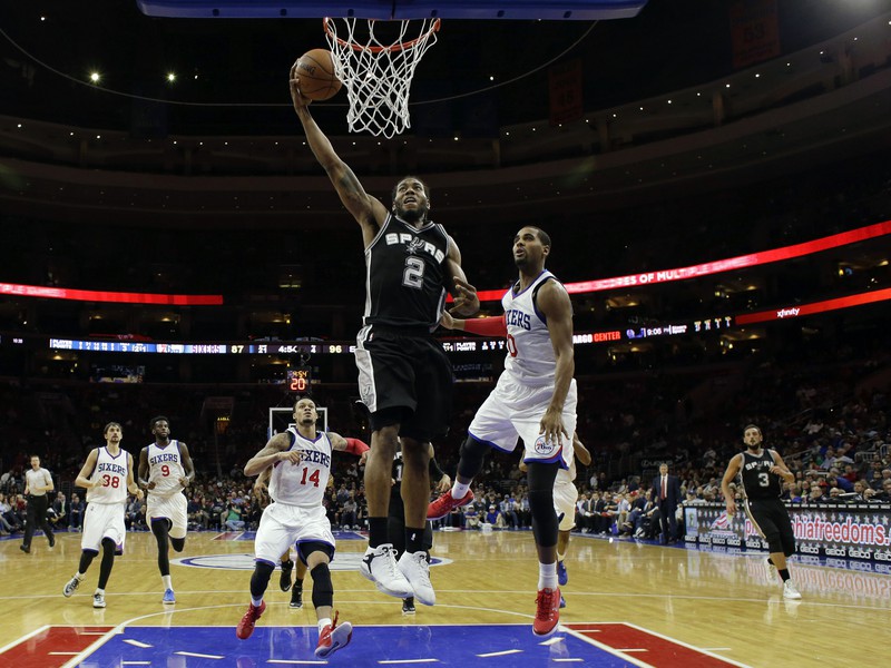 Kawhi Leonard (2) zo San Antonio Spurs strieľa pomedzi basketbalistov Philadelphie