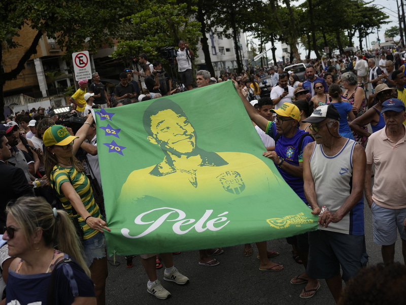 Ľudia držia baner s portrétom zosnulého brazílskeho legendárneho futbalistu Pelého počas prevozu jeho telesných pozostakov  zo štadióna Vila Belmiro na cintorín Memorial Necropole Ecumenica
