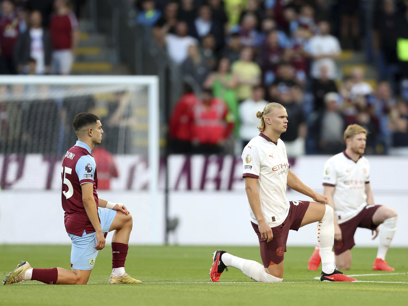 Zľava hráč Burnley Zeki Amdouni a hráči Manchestru City Erling Haaland a Kevin De Bruyne kľačia na kolenách pred začiatkom zápasu