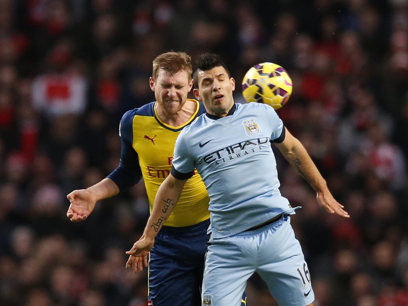 Per Mertesacker (vľavo) a Sergio Aguero v súboji o loptu