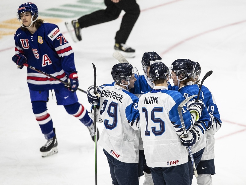 Americký hokejista Tanner Dickinson (vľavo) korčuľuje okolo hráčov Fínska, ktorí sa tešia po strelení gólu