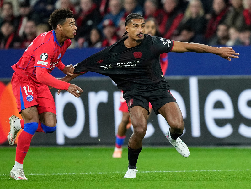 Hráč PSG Desire Doue (vľavo) ťahá za dres Loica Baldeho z Leverkusenu