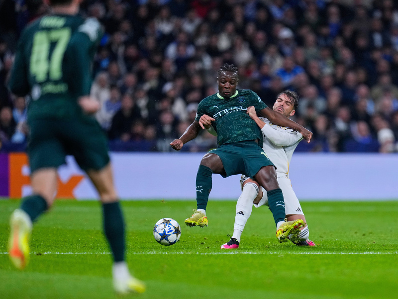 Hráč Manchestru City Jeremy Doku (vľavo) bojuje o loptu s Raúlom Asenciom z Realu Madrid