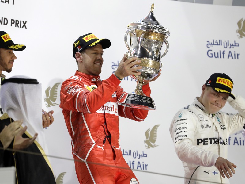 Nemecký pilot F1 na Ferrari Sebastian Vettel oslavuje na pódiu s trofejou 