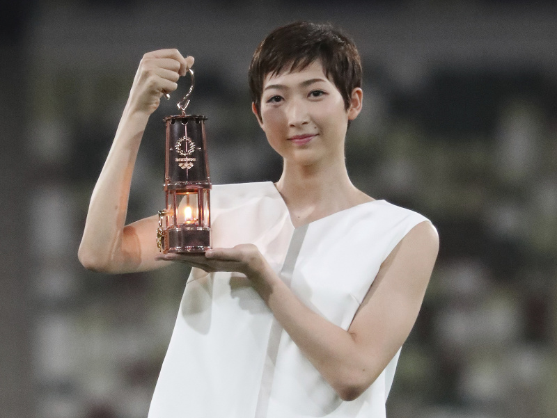 Rikako Ikeeová drží lampáš s olympijským ohňom