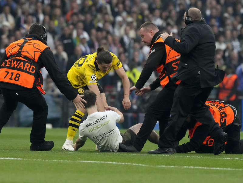 Pracovníci bezpečnostnej služby a hráč Borussie Dortmund Marcel Sabitzer (uprostred) chytajú futbalového fanúšika, ktorý prenikol na ihrisko počas finálového zápasu Ligy majstrov Borussia Dortmund - Real Madrid 